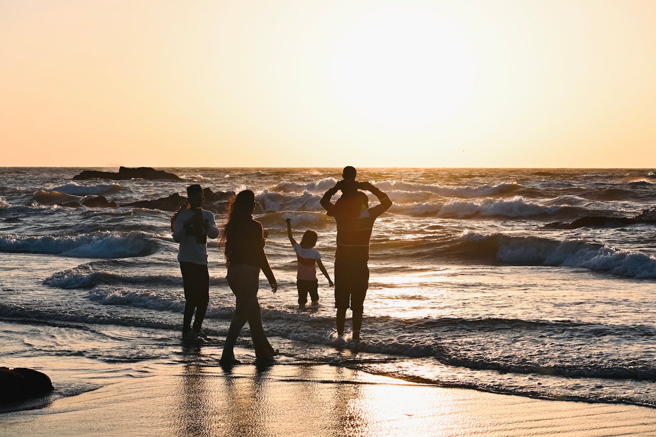services-01 Silhouetted family enjoying a vibrant sunset at a beach in Goa, India.