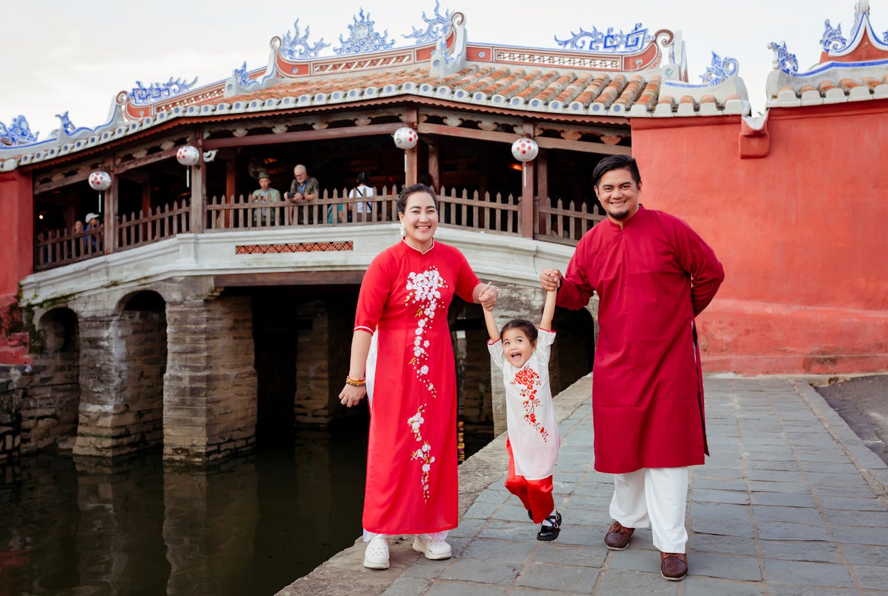 services-03 A family wearing red ao dai in front of the Japanese Covered Bridge in Hội An, Vietnam.